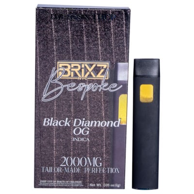 A black and yellow vape pen stands next to a tall box elegantly labeled: BRIXZ NYC Bespoke, Black Diamond OG, Indica, 2000MG, Tailor Made Perfection. A rich brown pattern graces the background of this BRIXZ NYC Bespoke THCP Disposable 2g delight.