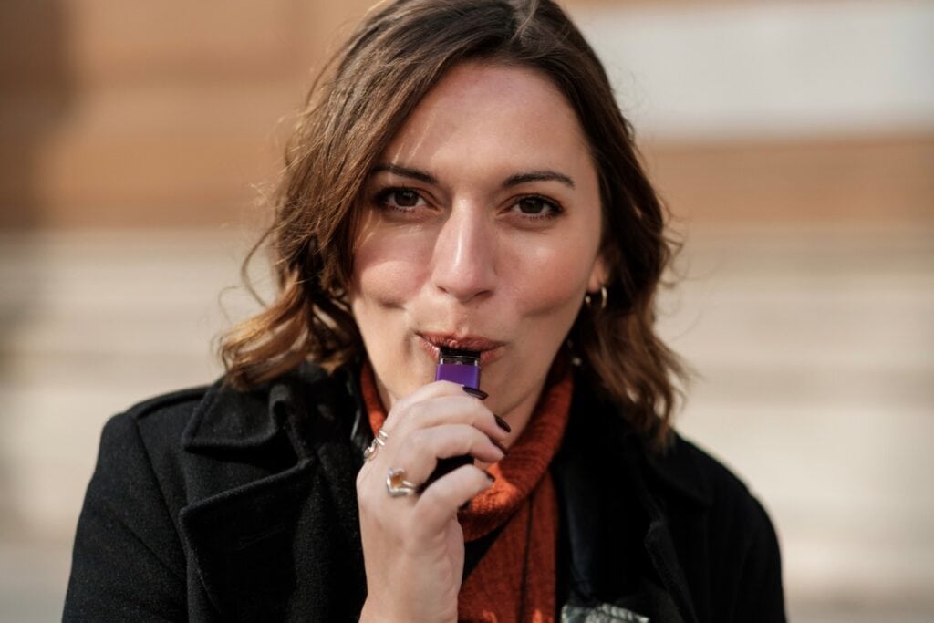 A lady is vaping a Muha Meds vape
