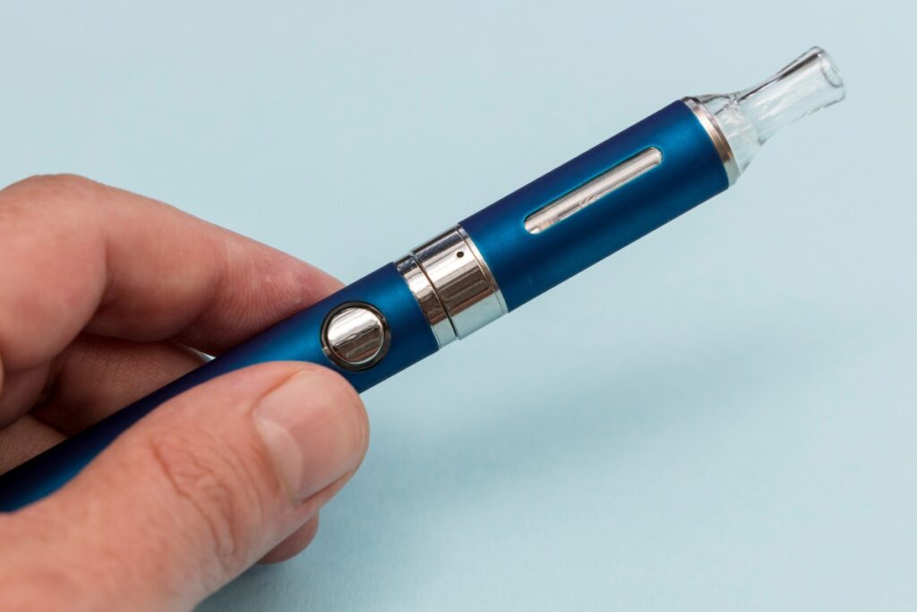 A person using a vaping device with button controls to enhance the vaping experience